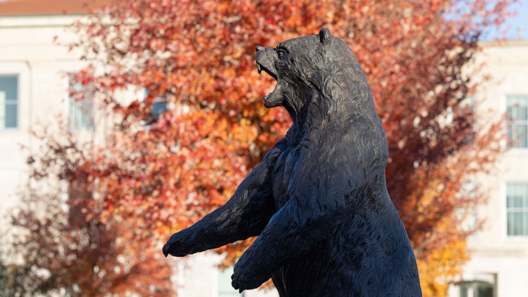 Bear statue with fall foliage in the background.