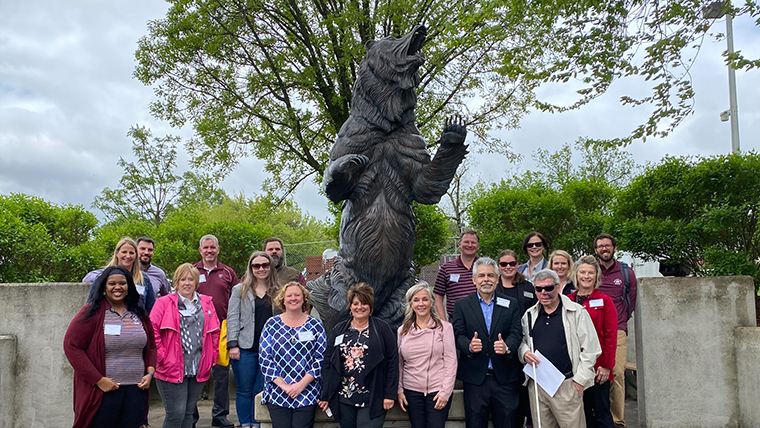 PAL program group taking picture with grizzly bear statue on the West Plains Campus