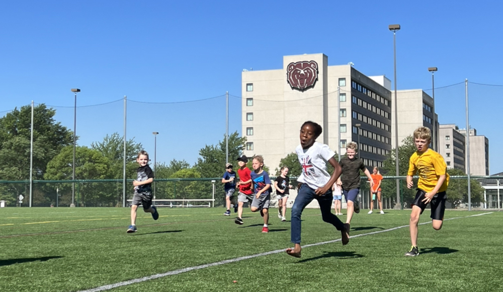 Children running on a soccer field.