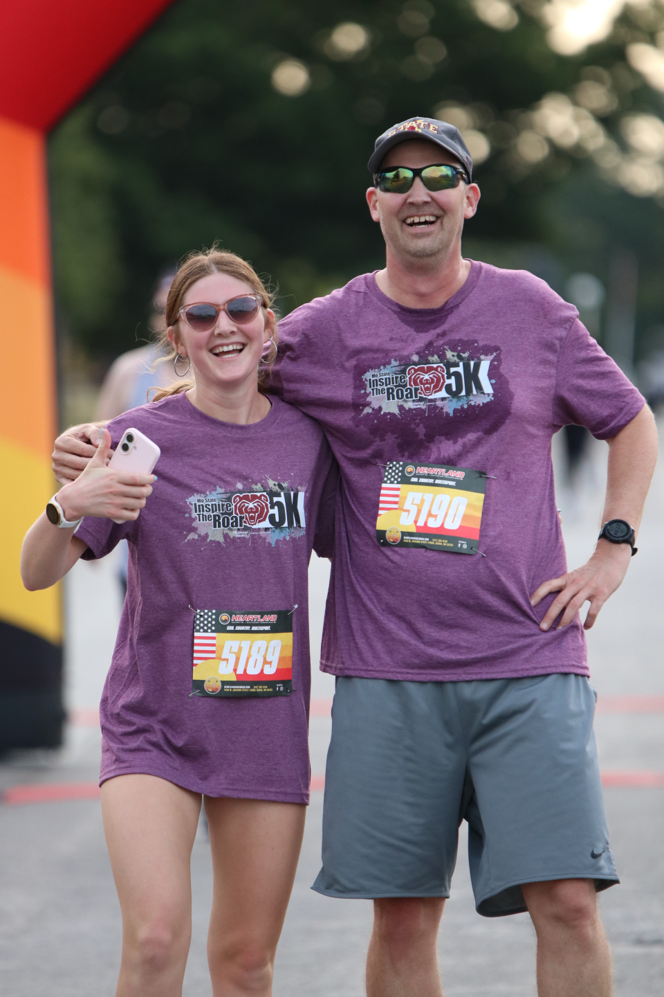 A father and daughter smiling after having run a race.