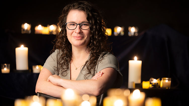 Portrait of Dr. Erin Wehrman, associate professor in the department of communication, media, journalism and film, as she is surrounded by candles.