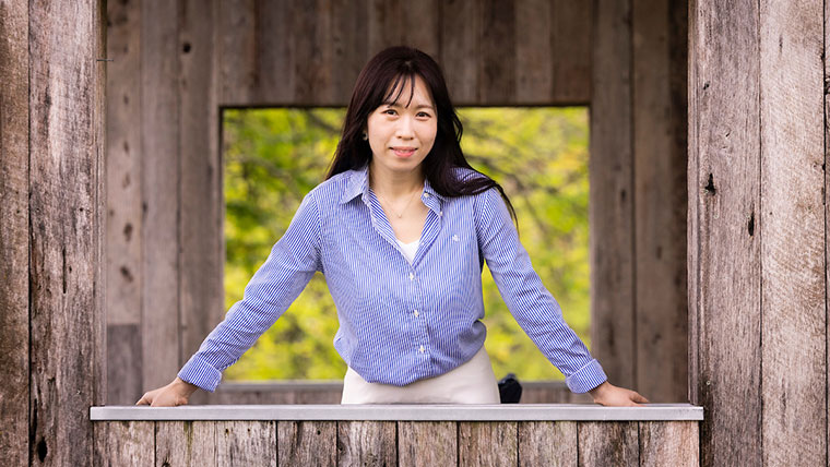 Portrait of Dr. Hailey Choi, associate professor in Missouri State's School of Teaching, Learning and Developmental Science, as she leans against an open window of a wooden building.