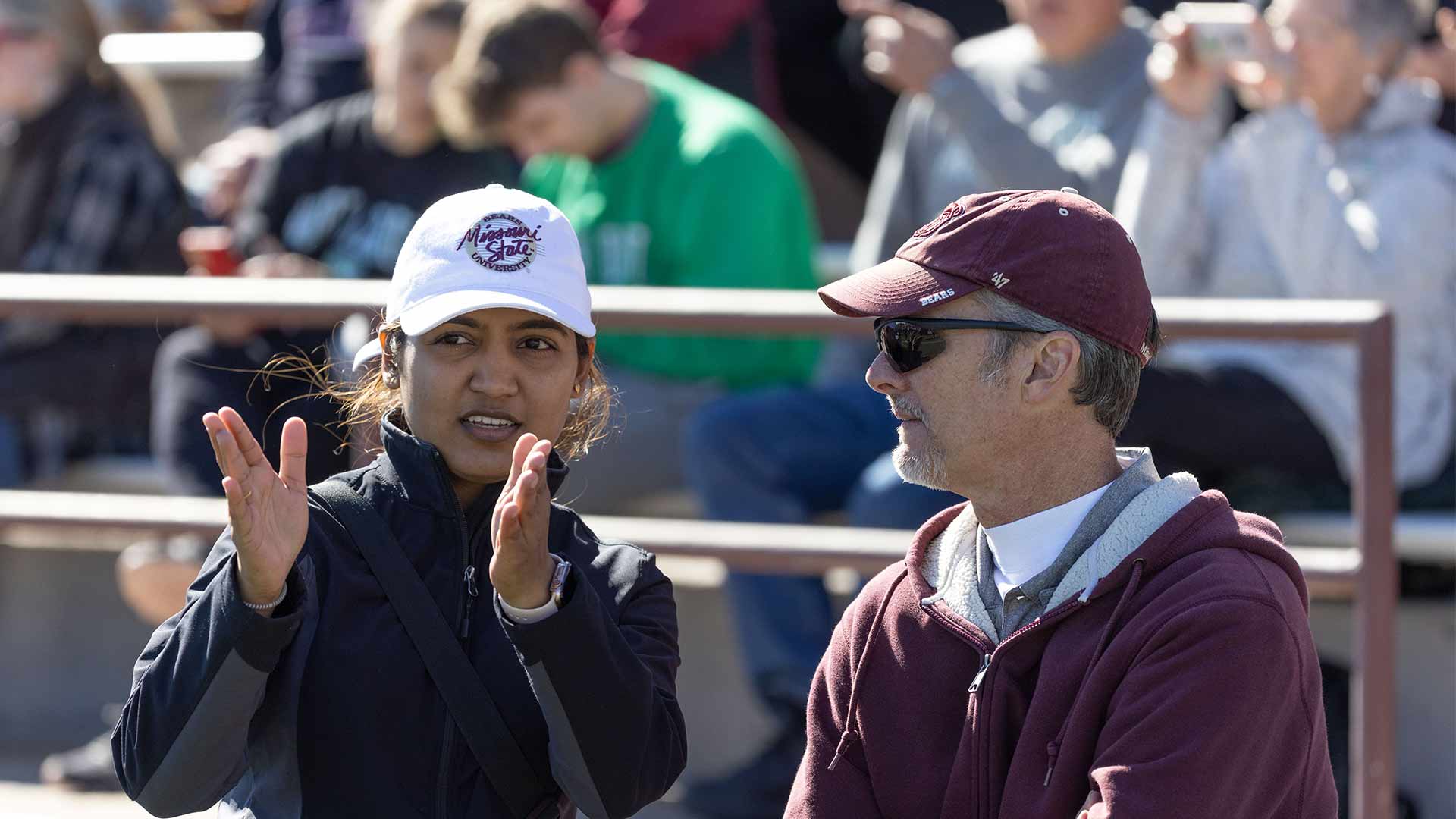 Two people talking on the sidelines during a Missouri State football game.