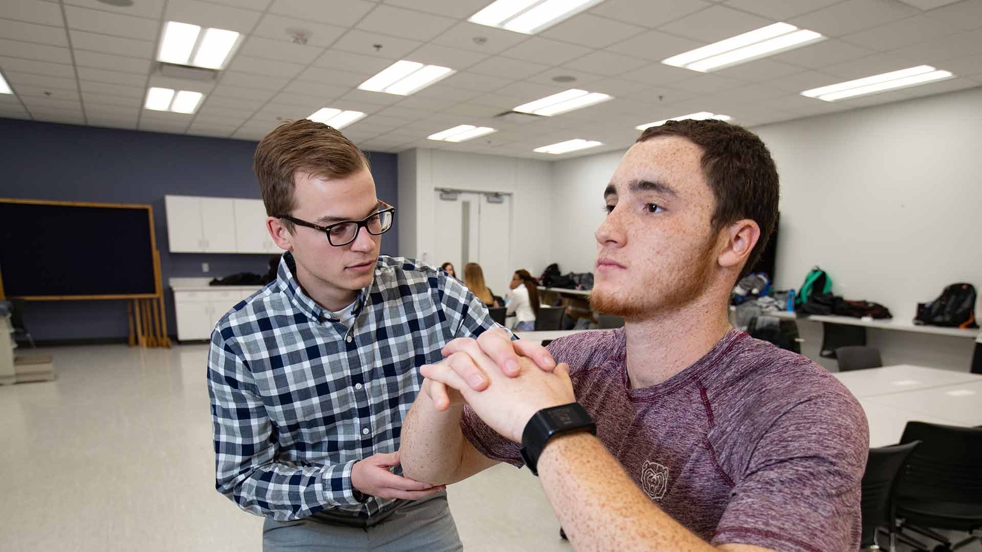 Athletic training student checking balance and flexibility on another student.