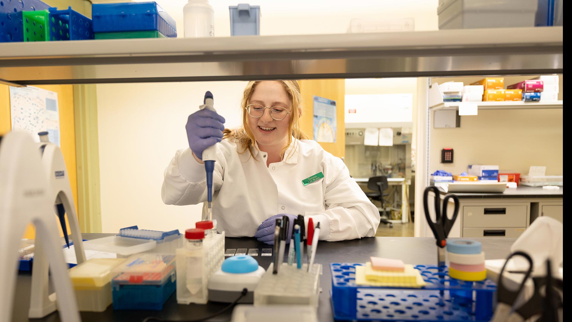 Science student in a white lab coat working in a research lab.