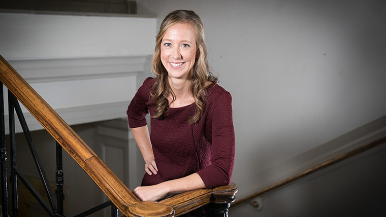 Dr. Adena Jones, psychology professor, posing next to a staircase in Hill Hall.