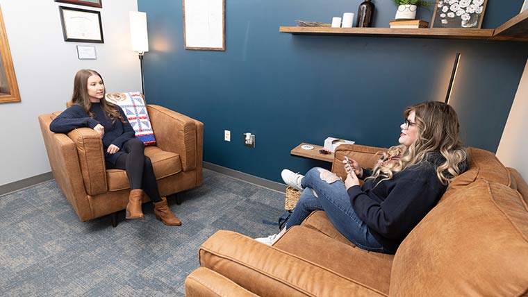 Student and professor talking in an office setting.