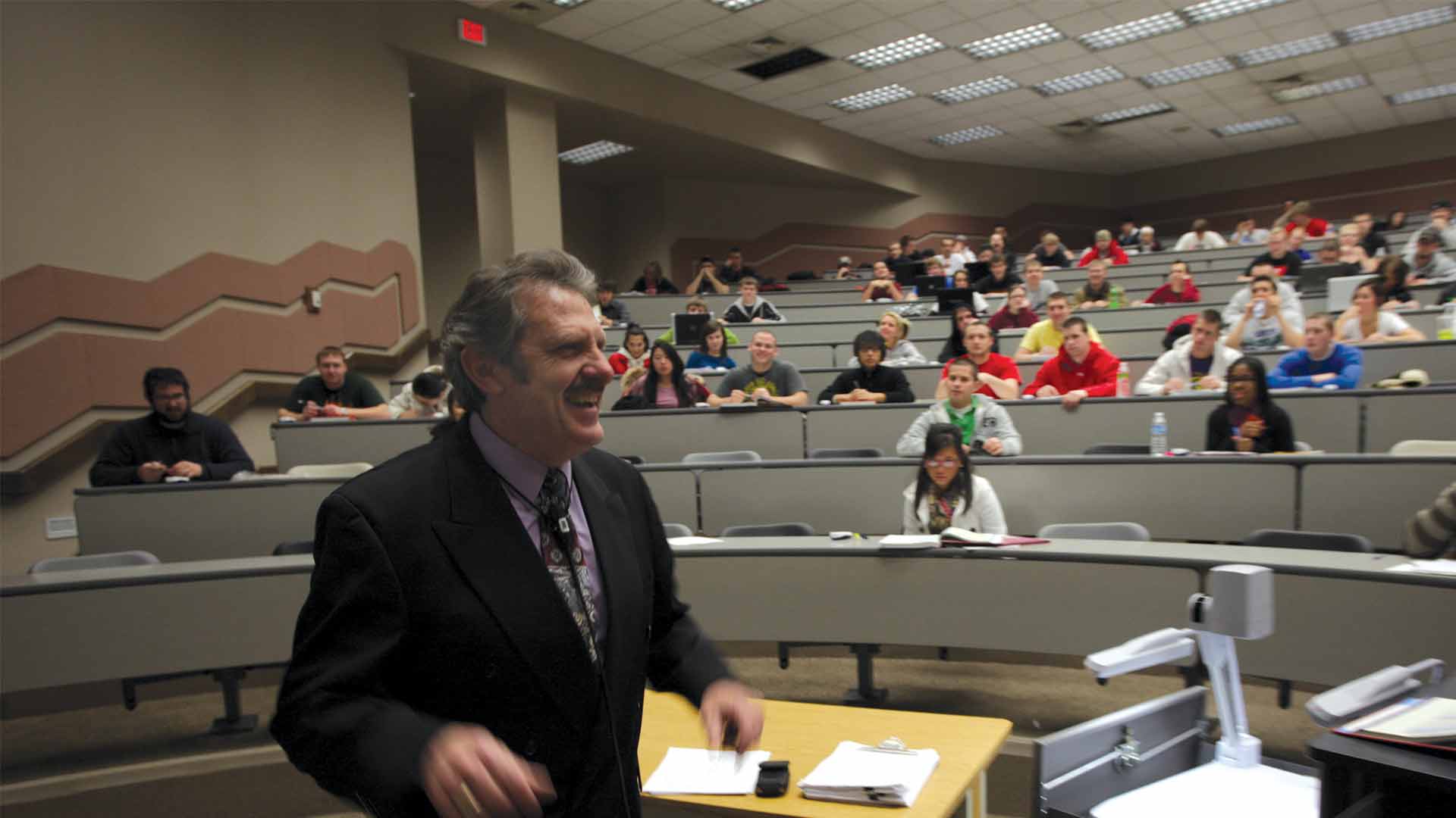 A smiling professor and his class during a lecture