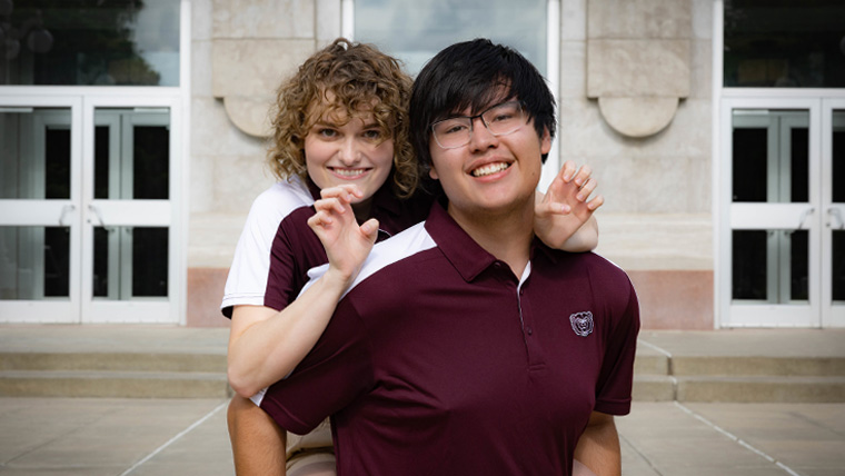 Two smiling Missouri State students in front of Carrington Hall.
