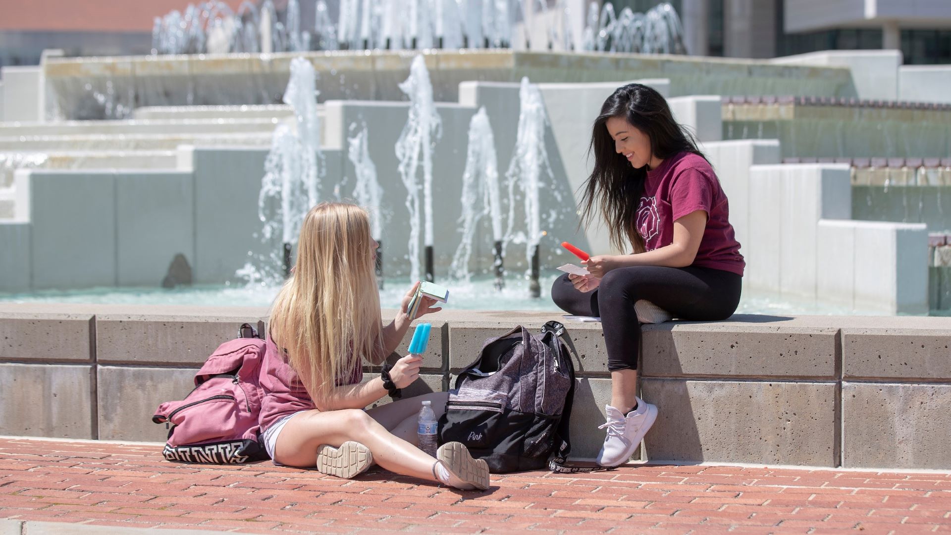 Two students enjoy a beautiful summer day at the John Q. Hammons Fountains