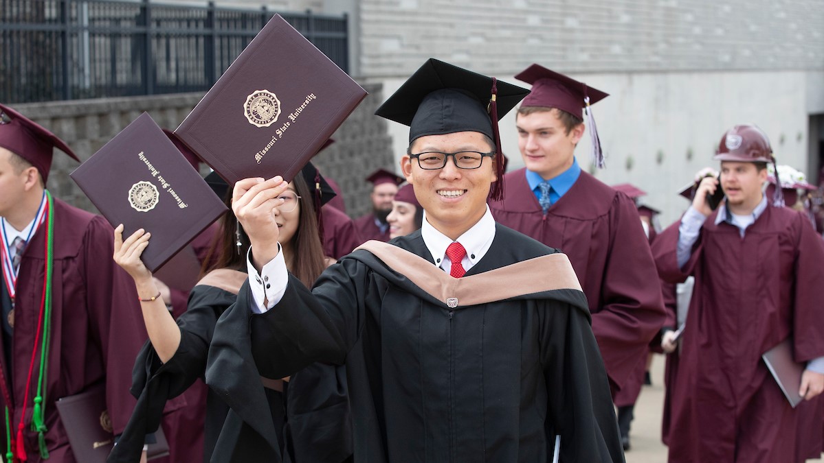 A Missouri State graduate student proudly displays his diploma cover on commencement day.