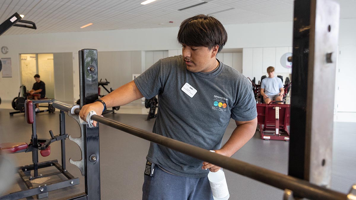 Male student wipes down work out equipment.