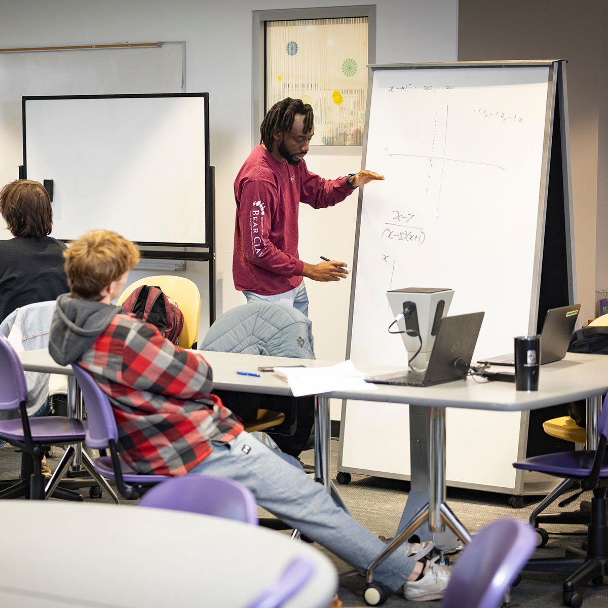 A tutor uses a white board to explain a math concept to a student in the Bear CLAW.