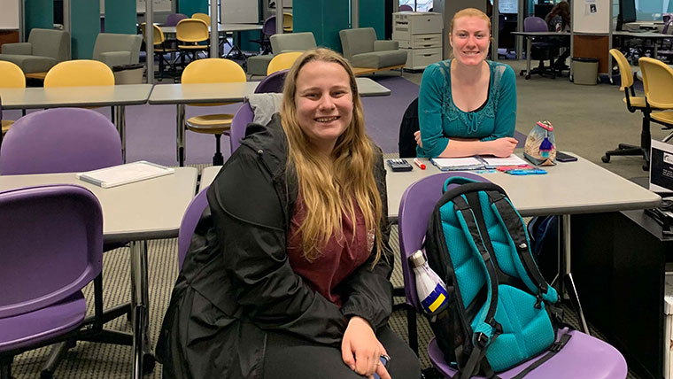 Two students at a table in the Bear CLAW smile at the camera