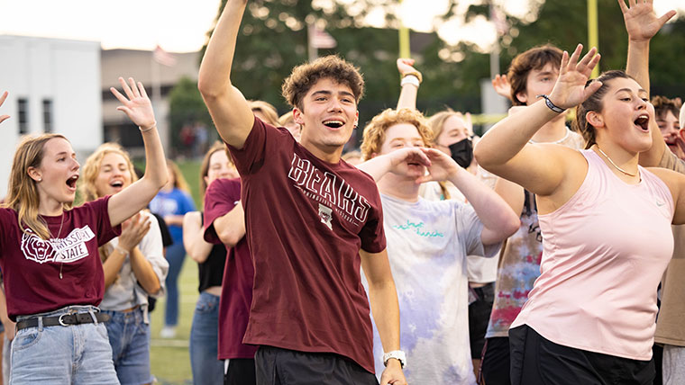 Students cheer and raise their hands excitedly on the Plaster Stadium field.