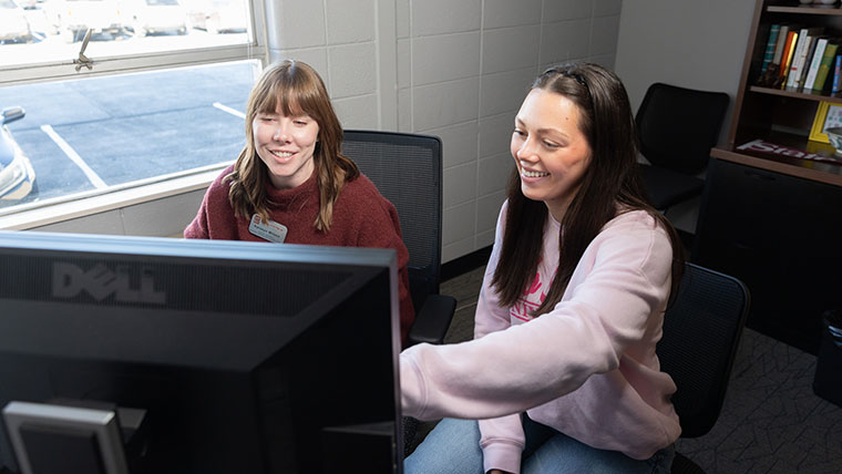 A Missouri State student discusses registration with her advisor and chooses her classes on a computer.