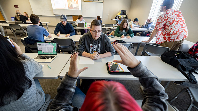 Students in Dr. Chelsea Davis' world history class discuss and draw an image of WWII propaganda on the screen at the front of the class.