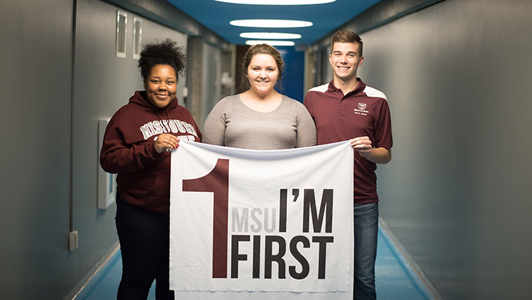 Three students holding an MSU "I'm First" banner to represent their first-generation student organization.