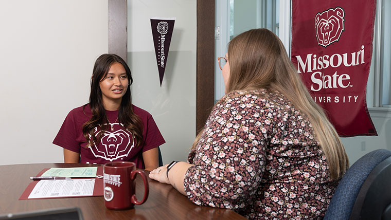 A new student discusses the admission process with a Missouri State employee.