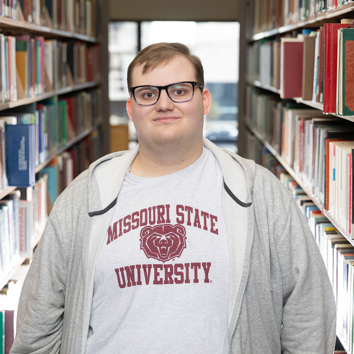 Daniel Paige, a senior at Missouri State, stands amidst the shelves of books in Meyer Library.