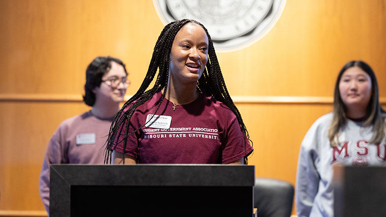 Tamia Schiele, study body president, gives a presentation with two other members of the Student Government Association standing behind her.