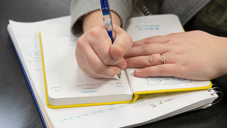 A student writes in a yellow journal.