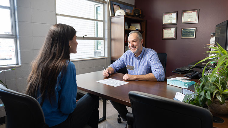 A student chats about her goals across a desk from Ross Hawkins, director of the Academic Advising and Transfer Center.
