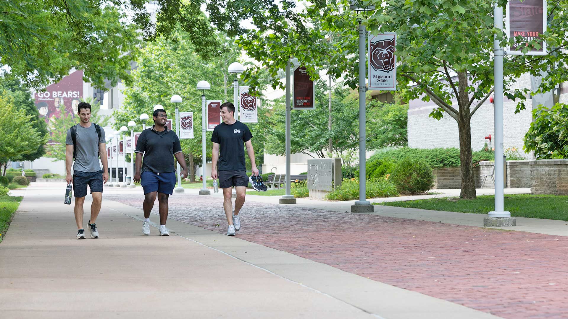 Three Missouri State students walking along the historic Kings Street lined with red brick. 