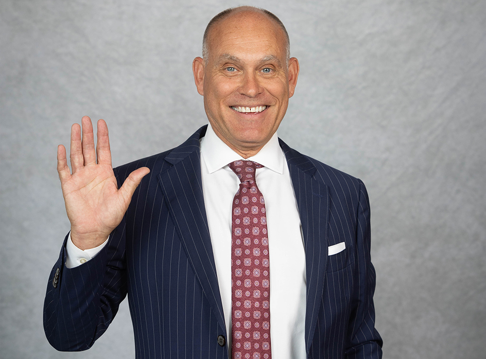 Studio photo of smiling Brent Dunn waving to the camera
