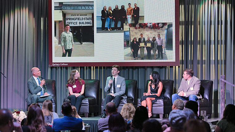 Award recipients sitting on a stage with host Brent Dunn.