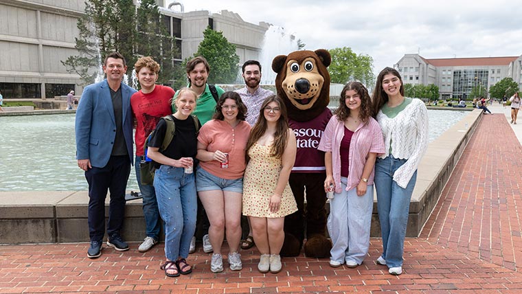 Missouri State students, faculty member and Boomer standing in front of Hammons Foundations. 