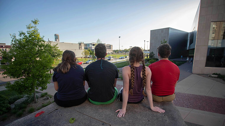 Four students sitting together looking out over campus.