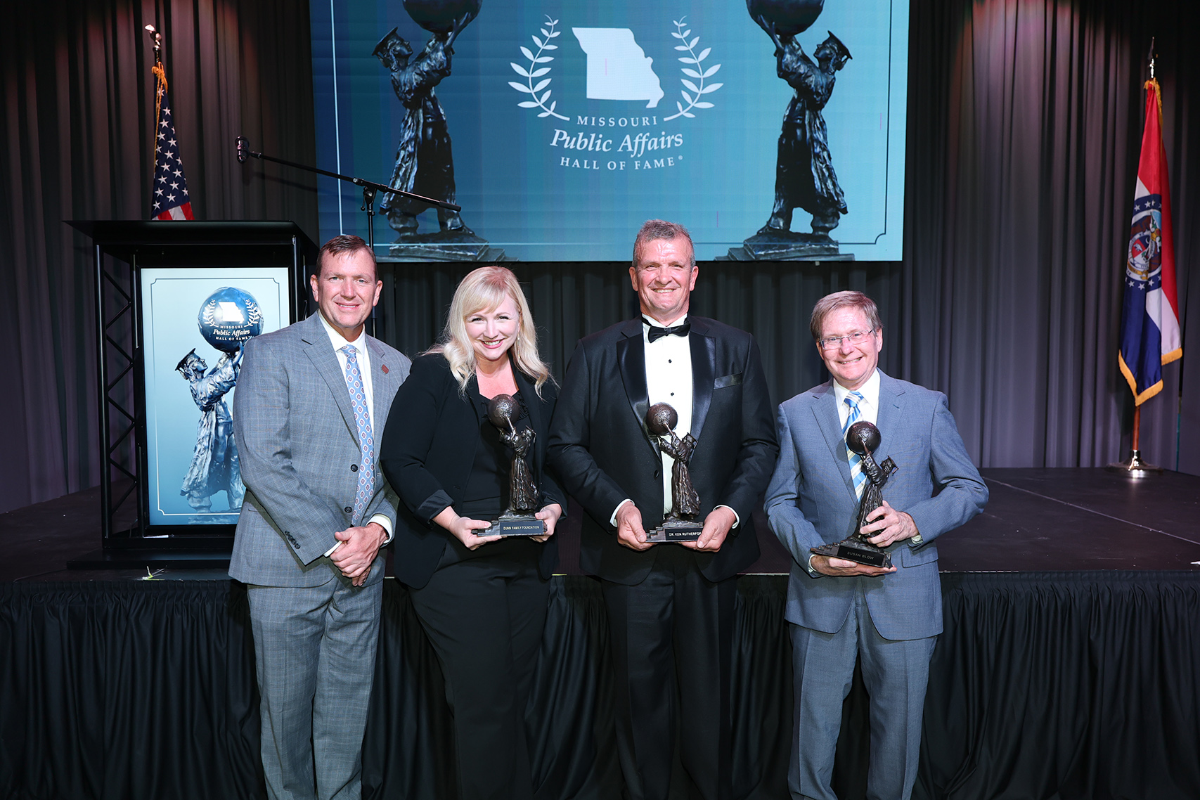 Photo of President Dr. Richard B. Williams and three honorees newly inducted into the Missouri Public Affairs Hall of Fame. All are smiling, the inductees are holding statues