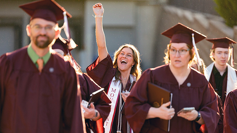 Four Missouri State graduates in cap and gown. 