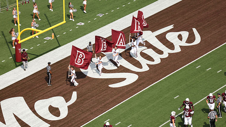 Spirit team running with flags on the Mo State football field.