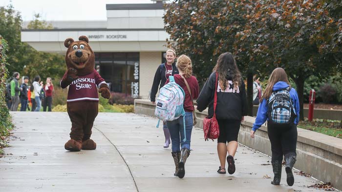 Boomer waving to students while walking on campus