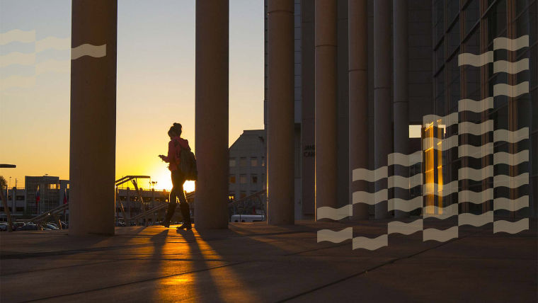 Outside the front entrance to Meyer Library at sunset with a silhouette of a student