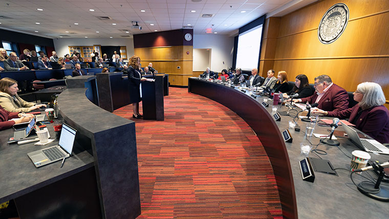 Individual at the podium presenting to the board of govenors.