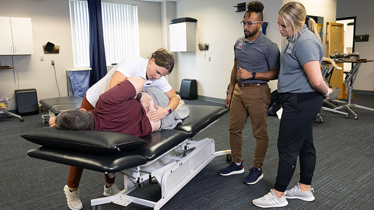 Dr. Kim Ennis demonstrating a physical therapy technique to others. 