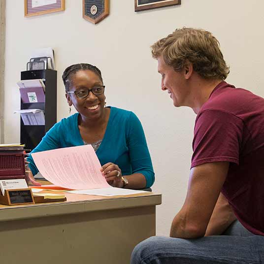 An advisor guides her student through documentation for his college journey.