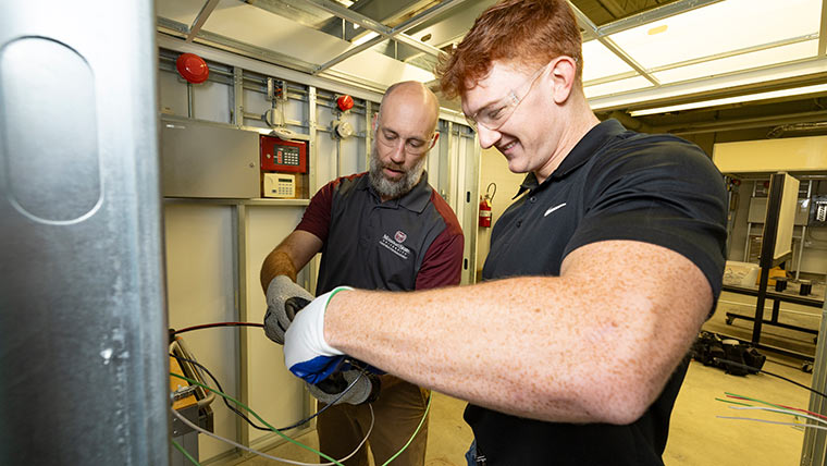 A construction technology student and professor work on wiring together in a lab.