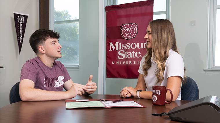 A student talks to an admissions counselor in an office on campus.