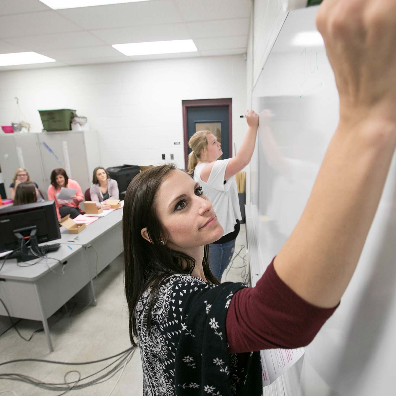 Two Missouri State education students write on a dry erase board during a class activity.