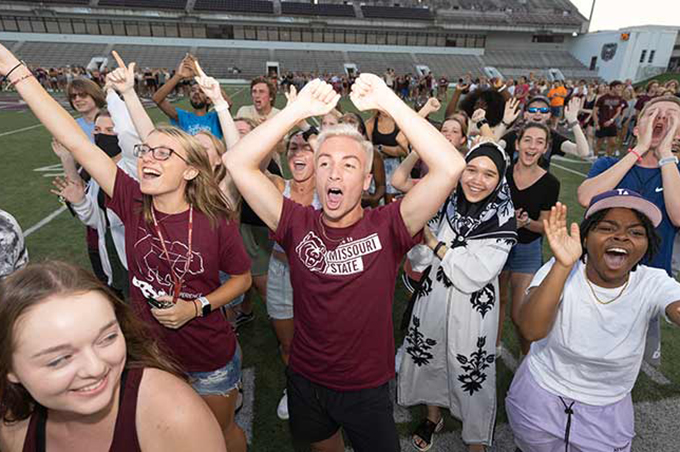 Excited students cheering while on the football field