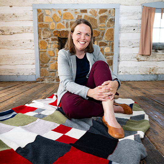 Dr. Philippa Koch, an associate professor of religion at Missouri State, is seated on a blanket on the floor to pose for a picture.