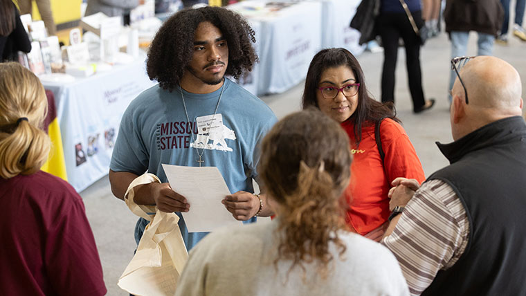A futute Bear and his mom talk to representatives from an academic department during Fall Showcase.