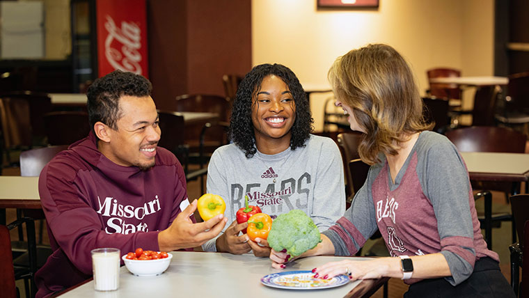 Three individuals holding vegetables and talking about Missouri State's nutrition and dietetics program.