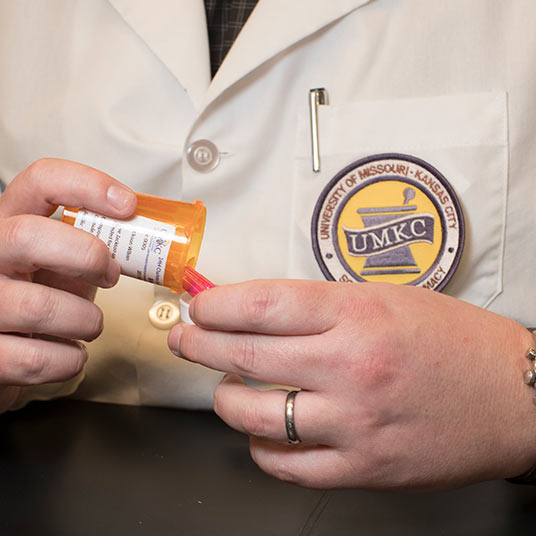 A person taking a pill out of a pill bottle.