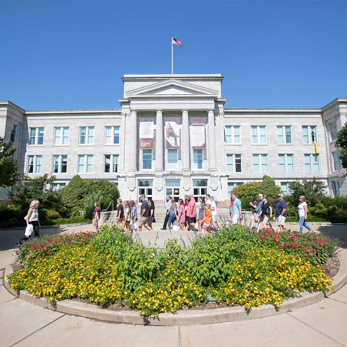 A tour group on Summer Visit Day walks in front of Carrington Hall.