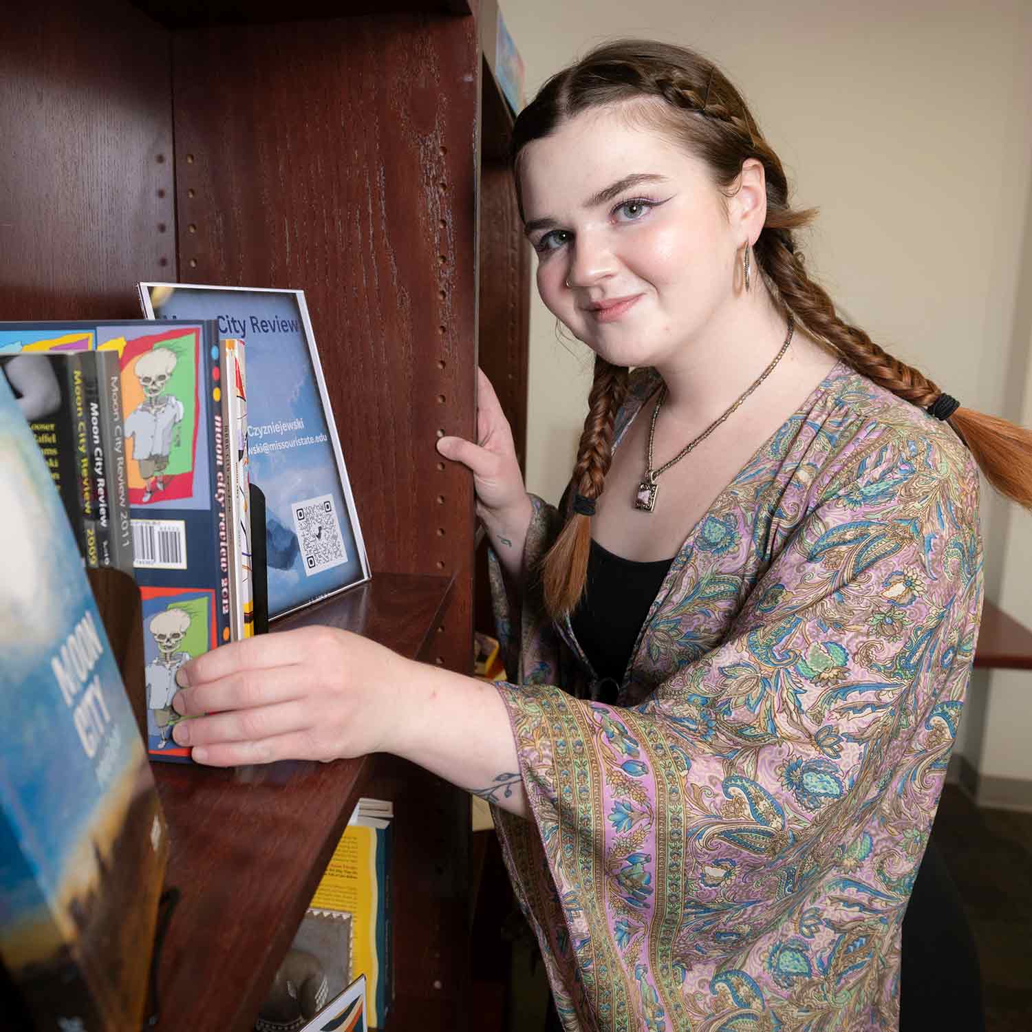 Alana Rowan, a graduate student in the English department, poses next to a bookcase inSiceluff Hall